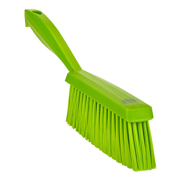 A close-up of a lime green Vikan soft hand brush.