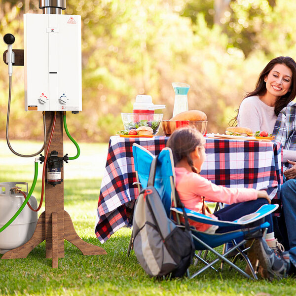 A man and woman using an Eccotemp outdoor water heater at a picnic table.