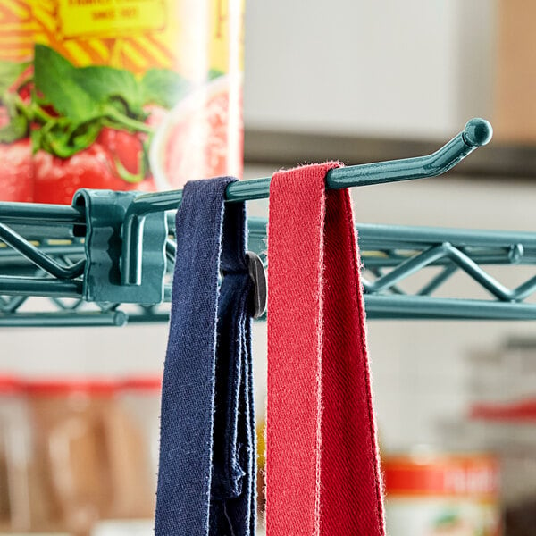 A pair of blue and red ties hanging from a Regency green epoxy ledge hook on a wire shelf.