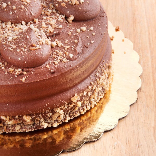 A 16" gold laminated corrugated cake circle with a chocolate cake and nuts on top.