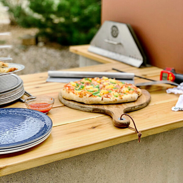 A Chicago Brick Oven countertop pizza oven with a pizza on a wooden board.