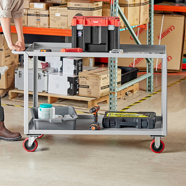 A man standing next to a Lavex steel utility cart with tools on it.