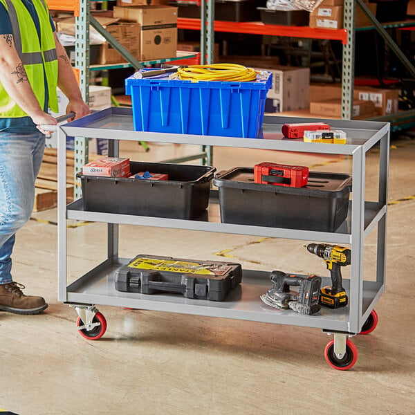 A man standing next to a Lavex utility cart with tools on it.