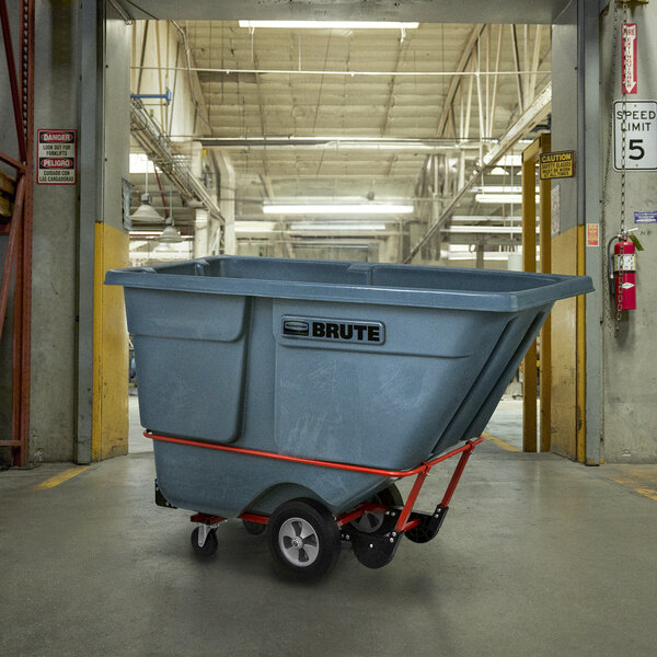 A large grey Rubbermaid BRUTE trash cart on a red metal frame.