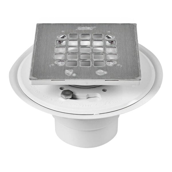 A white PVC Oatey shower drain with a square brushed nickel metal strainer.