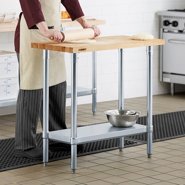 A woman rolling dough on a Regency wood top work table.