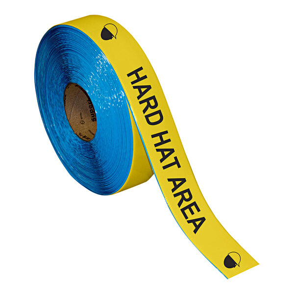 A roll of yellow and black Superior Mark safety tape with the words "Hard Hat Area" in black.