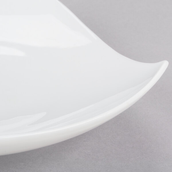 A CAC bone white porcelain peach plate with a curved edge on a gray surface.