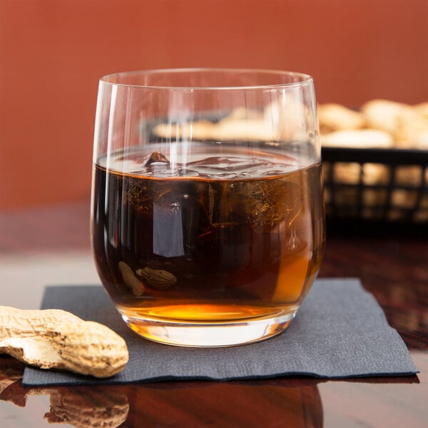 A Stolzle Grand Cuvée double old fashioned glass with ice and a peanut on the table.