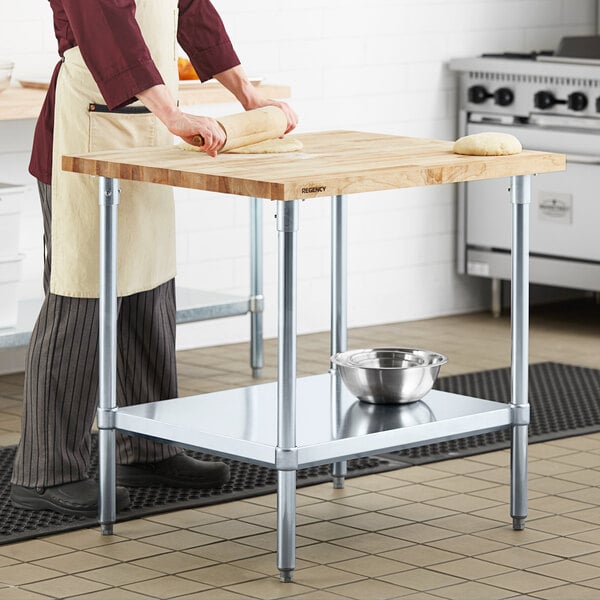 A woman rolling dough on a Regency wood top work table.