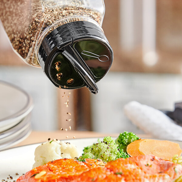 A black dual flapper spice lid with 3 holes pouring pepper onto food.