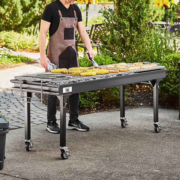 A man grilling corn on a Backyard Pro charcoal grill set up on a table outdoors.
