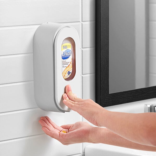 A hand using a Dial Versa light gray cartridge bottle manual soap dispenser.