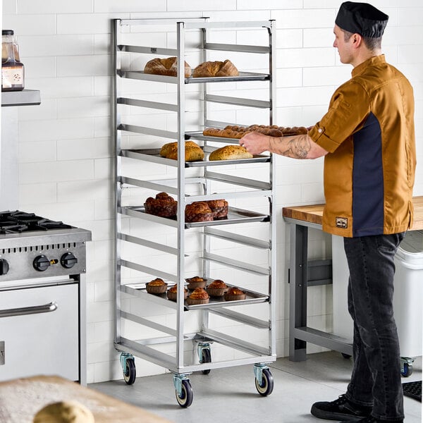 A heavy-duty aluminum bun and sheet pan rack with 12 end load slots, shown holding trays of baked goods in a commercial kitchen.
