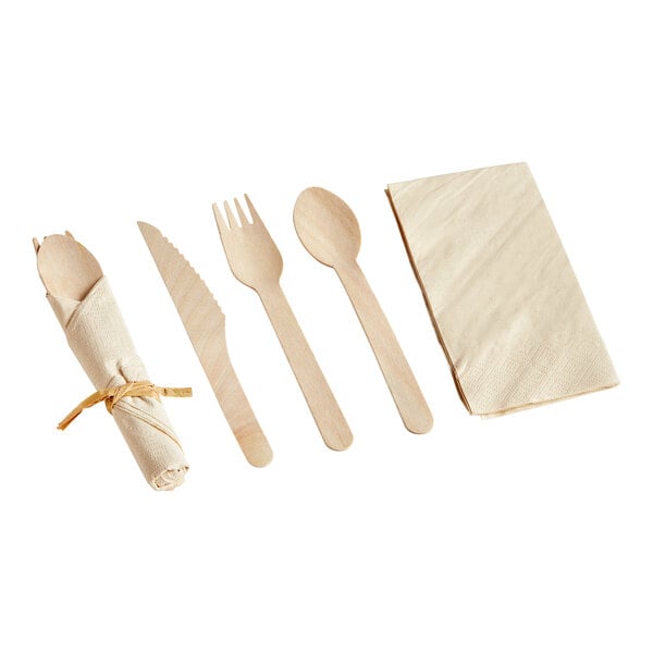 A Hoffmaster CaterWrap FashnPoint natural kraft napkin and wood cutlery set with a wooden spoon, fork, and knife wrapped in a napkin.
