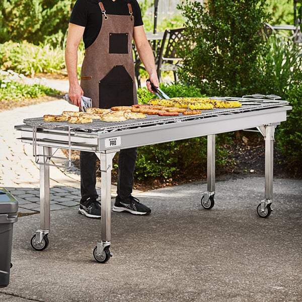 A man cooking food on a large stainless steel charcoal grill.