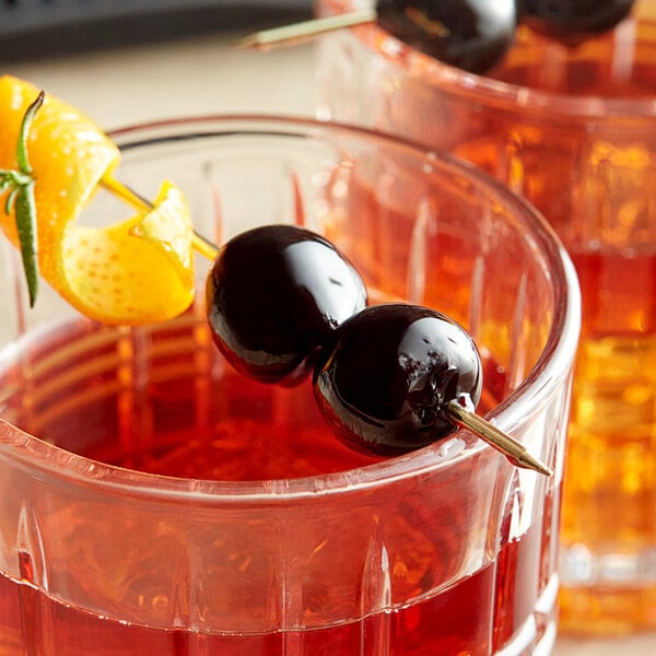 Two glasses of cocktails garnished with Luxardo Maraschino cherries.