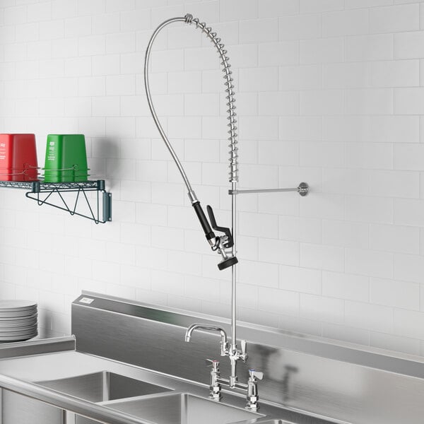 A Regency deck-mounted pre-rinse faucet with an attached hose above a stainless steel sink.