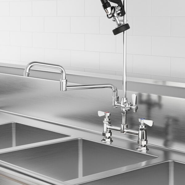 A stainless steel sink with a Regency pre-rinse add-on faucet and double-jointed swing spout over it.