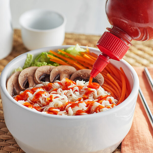 A bowl of noodles and vegetables with Pride O' Thai Sriracha Sauce.