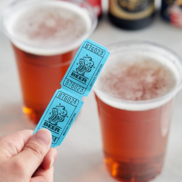 A hand holding a blue "Beer" raffle ticket in front of two cups of beer.