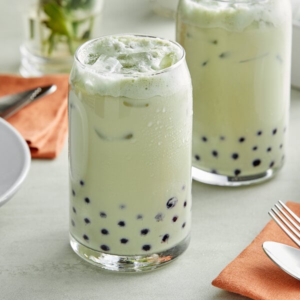 A glass of green Thai tea with ice and mint.