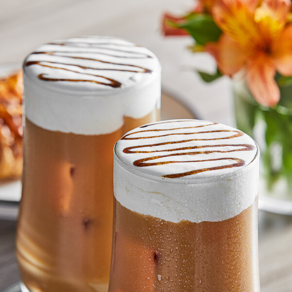 Two glasses of Fanale vanilla drinks with whipped cream and brown liquid.