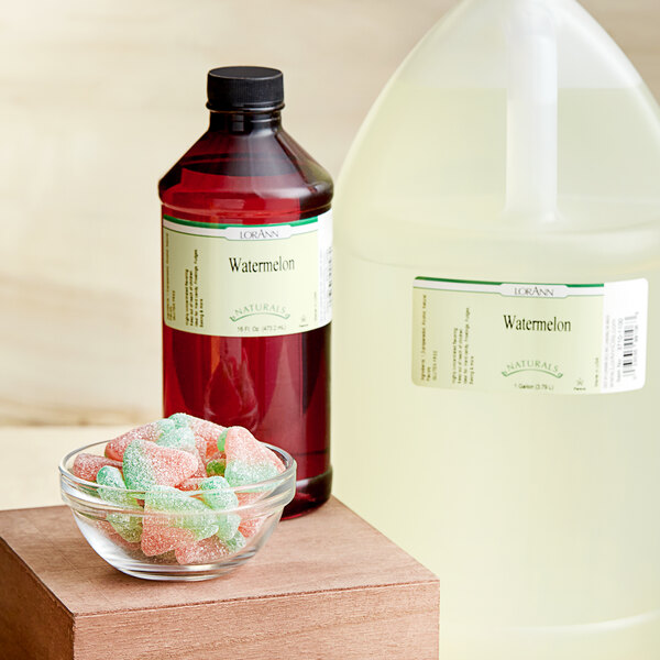 A bowl of candy next to a bottle of LorAnn Oils Watermelon Natural Flavor.