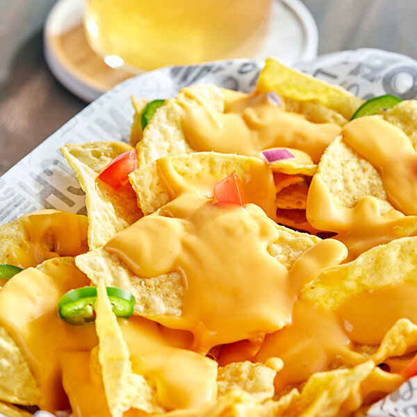 A plate of nachos with Muy Fresco vegan cheese sauce and jalapenos.