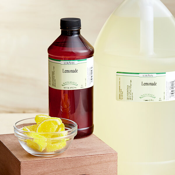 A bottle of LorAnn Oils Lemonade Natural Flavor next to a bowl of lemons.