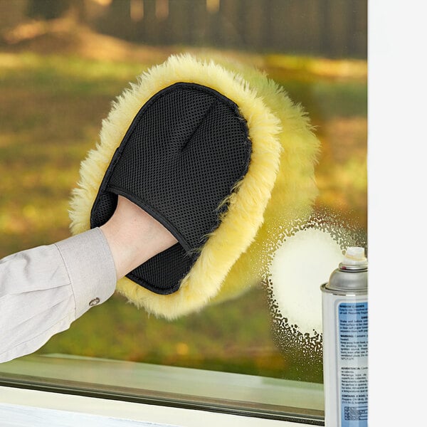 A hand using a Lavex sheep skin cleaning mitt to clean a window.