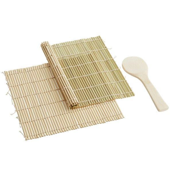 A bamboo sushi mat next to a bamboo rice paddle.