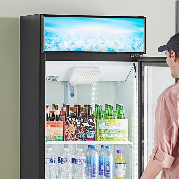 A man looking at a blue Avantco graphic sign panel on a refrigerator.