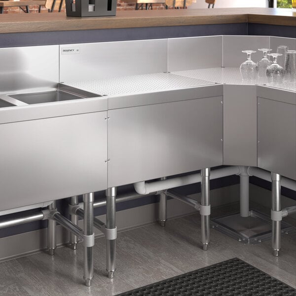 A Regency stainless steel underbar drainboard on a kitchen counter.