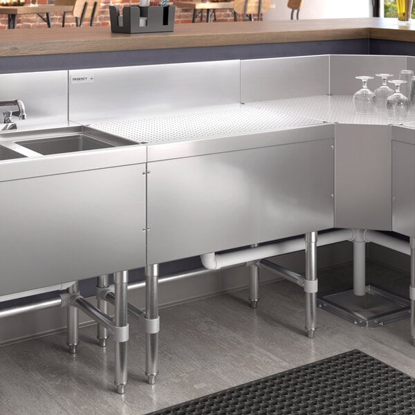 A Regency stainless steel underbar drainboard on a counter.