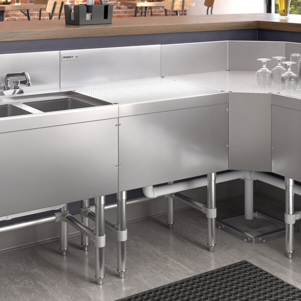 A Regency stainless steel underbar drainboard on a counter in a professional kitchen.