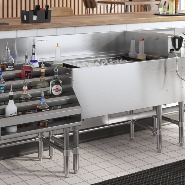 A Regency stainless steel underbar ice bin with post-mix cold plate and bottle holders on a counter.