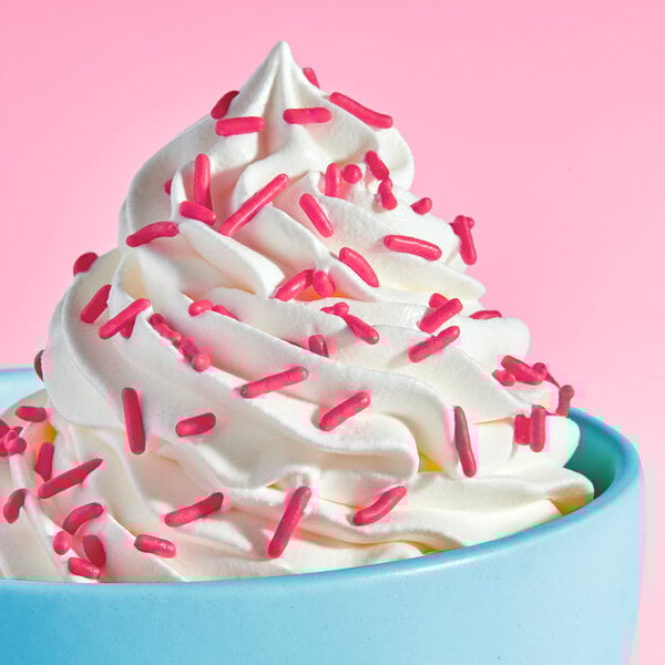A swirl of soft serve ice cream topped with pink sprinkles in a blue bowl.