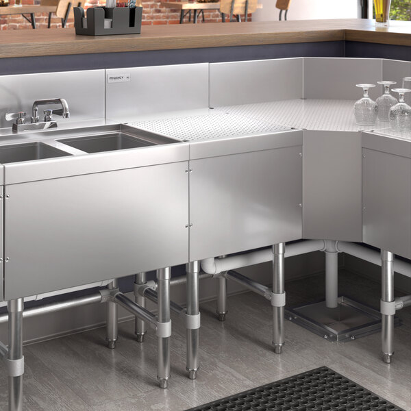 A Regency stainless steel underbar drainboard on a counter in a kitchen with a sink and counter.
