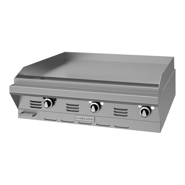A stainless steel modular top griddle with three control knobs and a flat cooking surface.