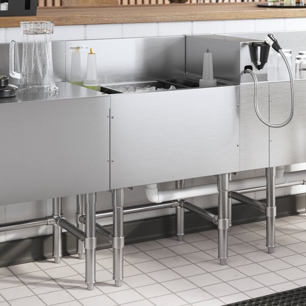 A Regency stainless steel underbar ice bin with a cold plate and bottle holders on a counter.