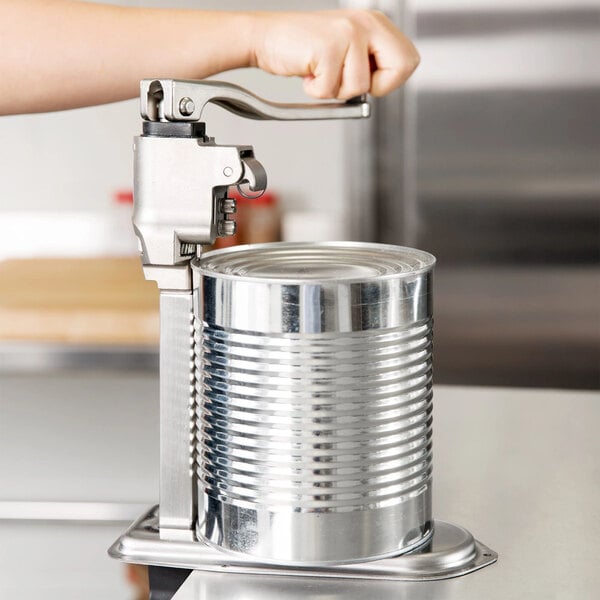 A heavy-duty commercial can opener with a long bar being used to open a large metal can.