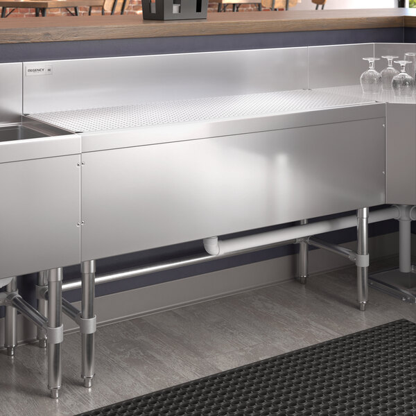 A Regency stainless steel underbar drainboard on a counter with a sink.