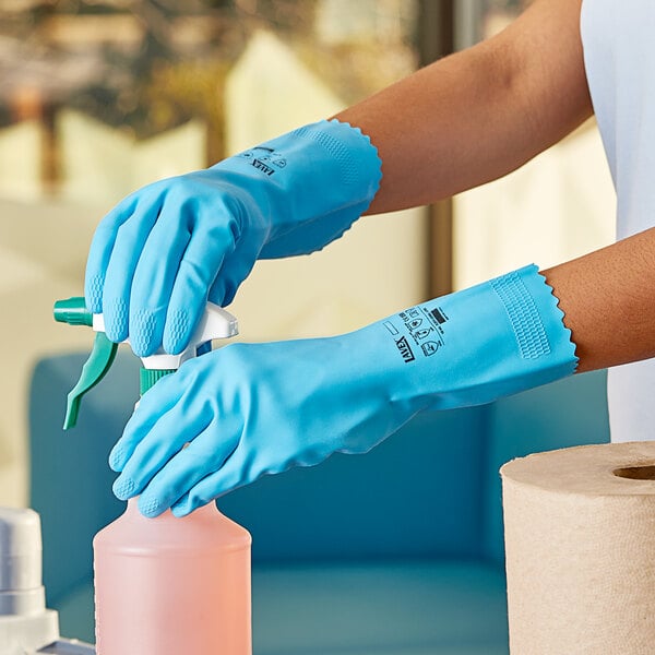 A person wearing blue Lavex gloves using a spray bottle.