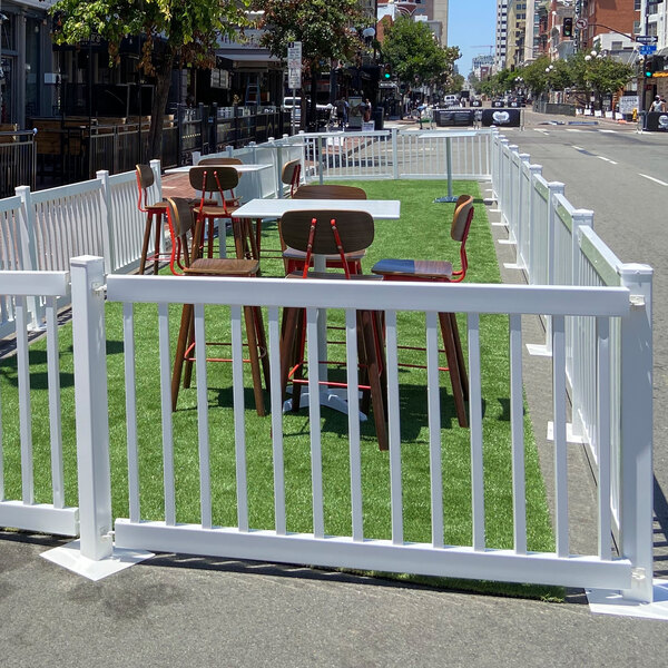Mod-Traditional white fence with tables and chairs with red legs on a green lawn