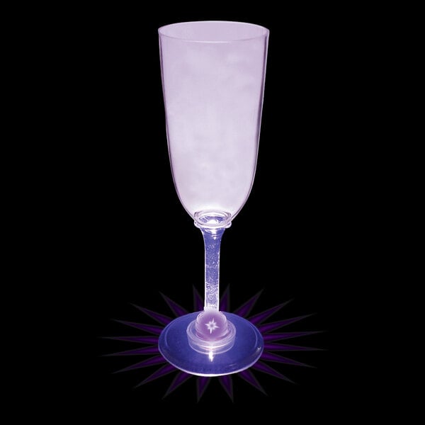 A clear plastic champagne cup filled with a purple drink illuminated by a purple LED light.