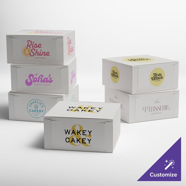 A group of white customizable cake boxes with different colored text on them.