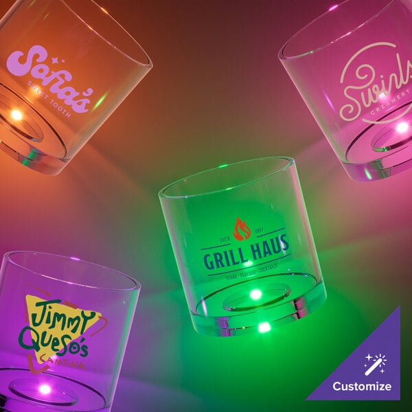 A customizable plastic rocks cup with a green LED light on a table in a cocktail bar.