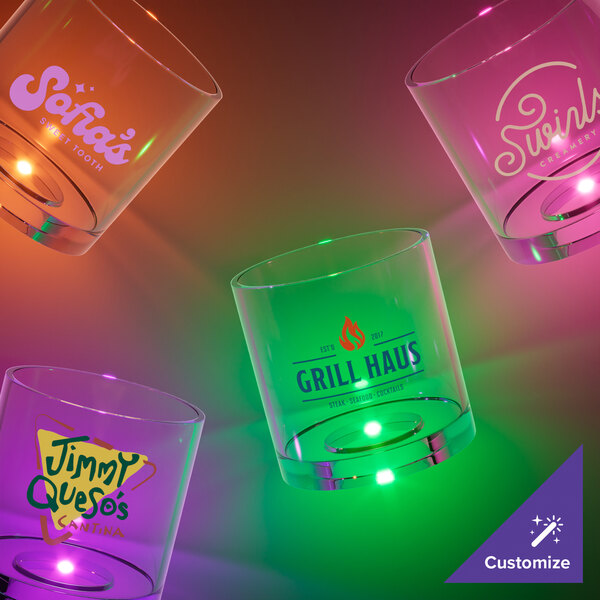 A customizable plastic rocks cup with an orange LED light on a table in a cocktail bar.