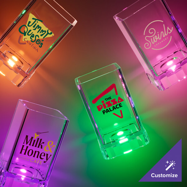 A group of customizable square shot glasses with orange LED lights on a table.